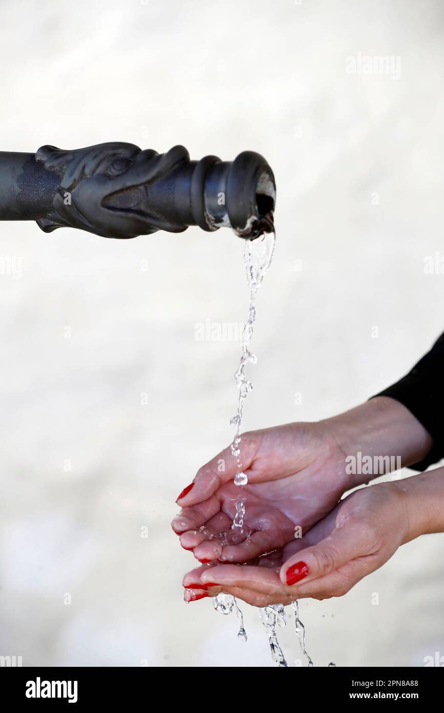 Acqua che scorre da una fontana nelle mani di una donna. Foto Stock