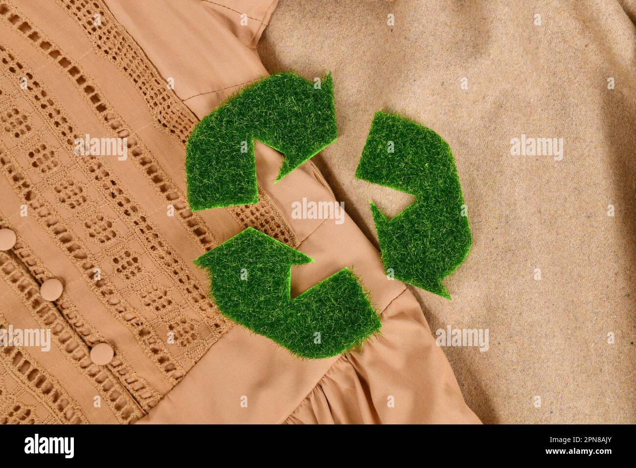Concetto per abbigliamento ecologico con simbolo a freccia di riciclaggio in erba Foto Stock