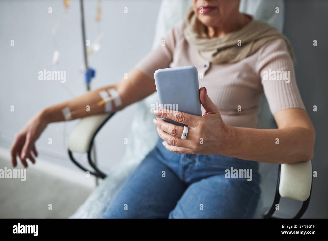 Primo piano della donna anziana che usa lo smartphone durante il trattamento chemioterapico, copia spazio Foto Stock