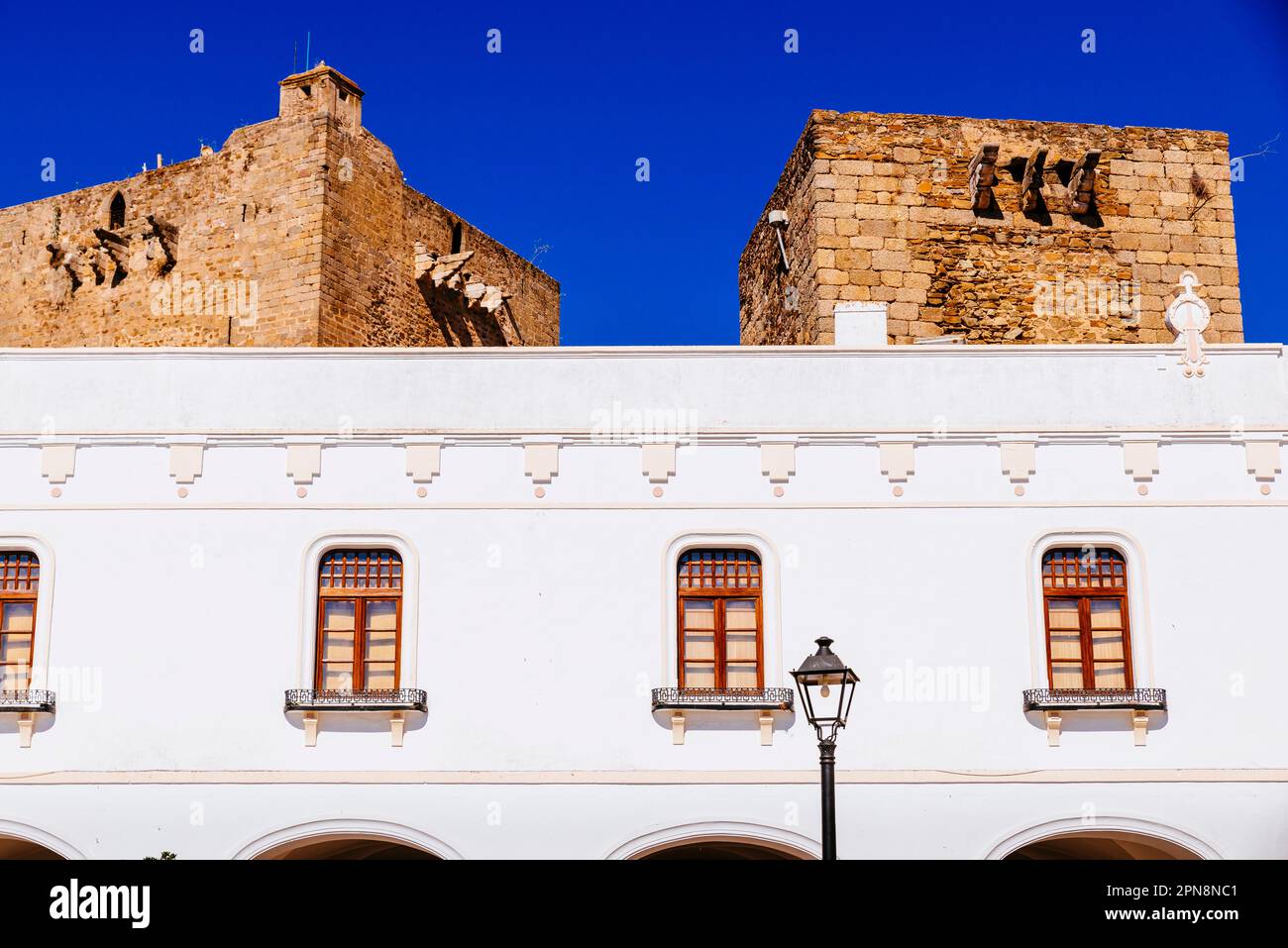 Le imponenti torri del Castello appaiono dietro l'ex Camera di Agricoltura. Olivenza, Badajoz, Estremadura, Spagna, Europa Foto Stock