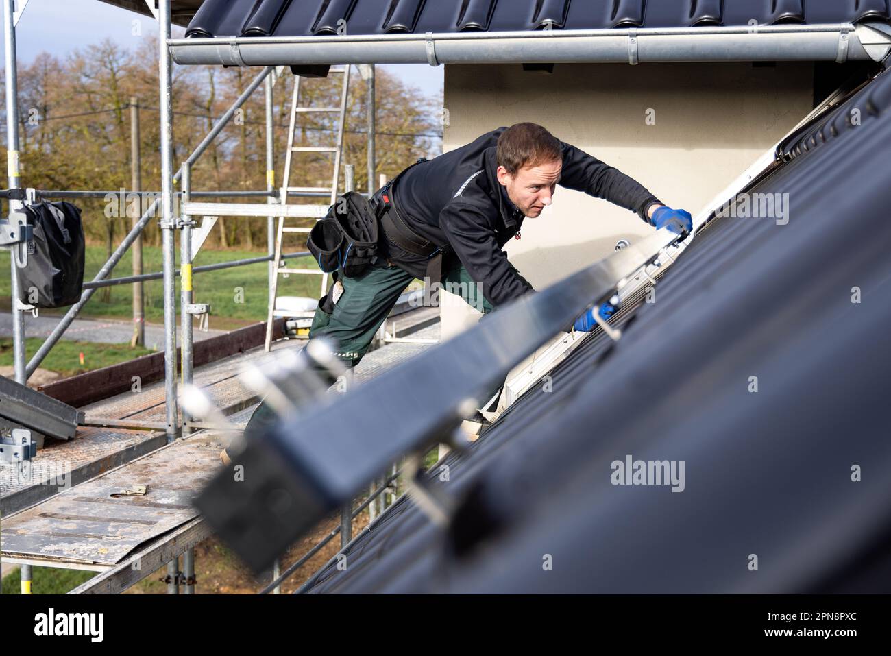 Artigiano che installa strutture di supporto pannelli solari sul tetto di una casa singola tedesca Foto Stock
