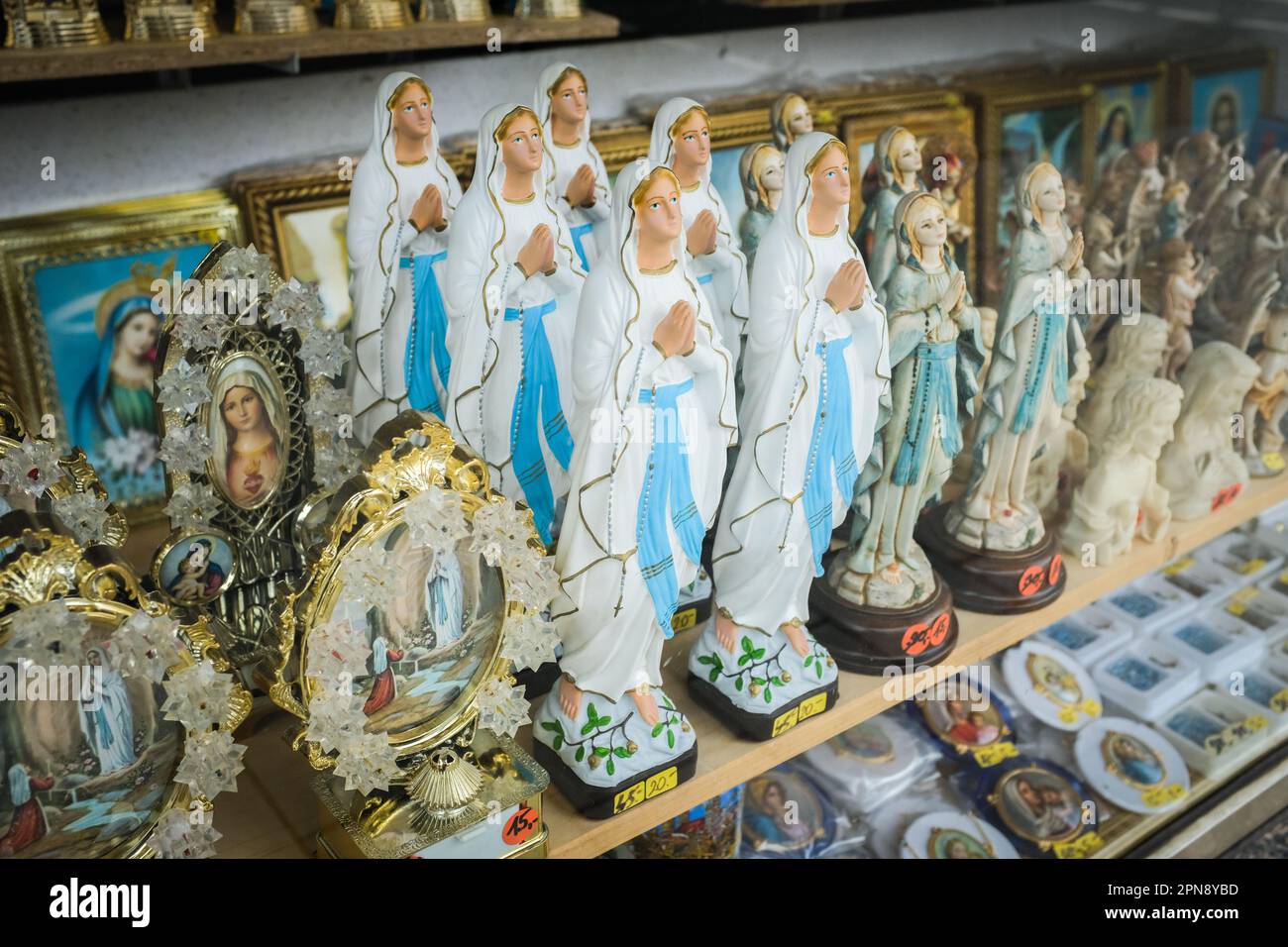 Statuette e altre iconografie religiose della Vergine Maria in una vetrina a Monaco di Baviera, Germania. Foto Stock