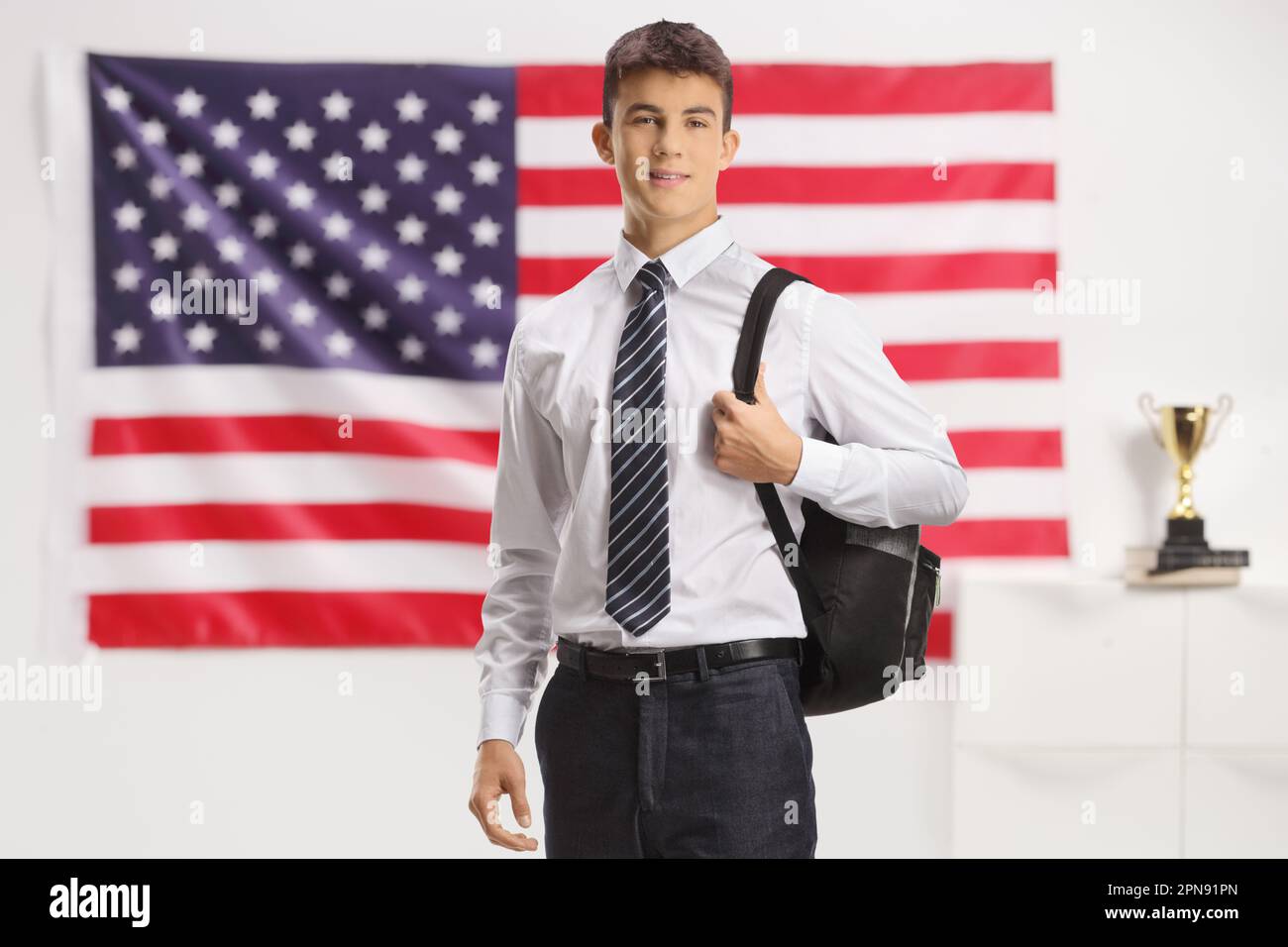Allievo caucasico maschio che posa davanti alla bandiera degli Stati Uniti Foto Stock