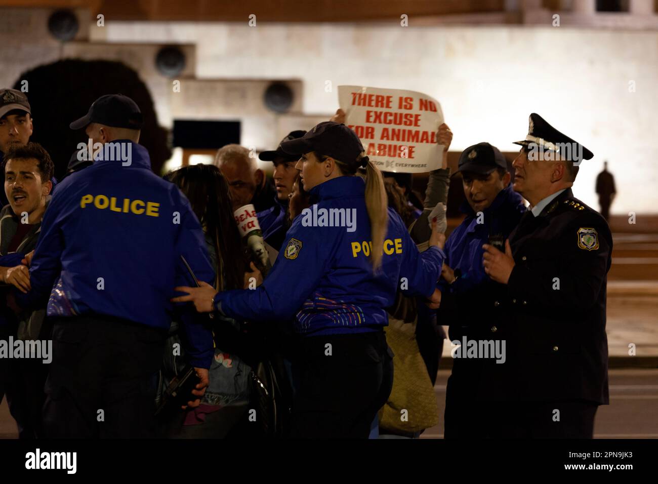 Protesta degli attivisti vegani contro gli abusi sugli animali e il consumo di carne durante i festeggiamenti pasquali, mentre i poliziotti in uniforme blu li spingono indietro. Foto Stock