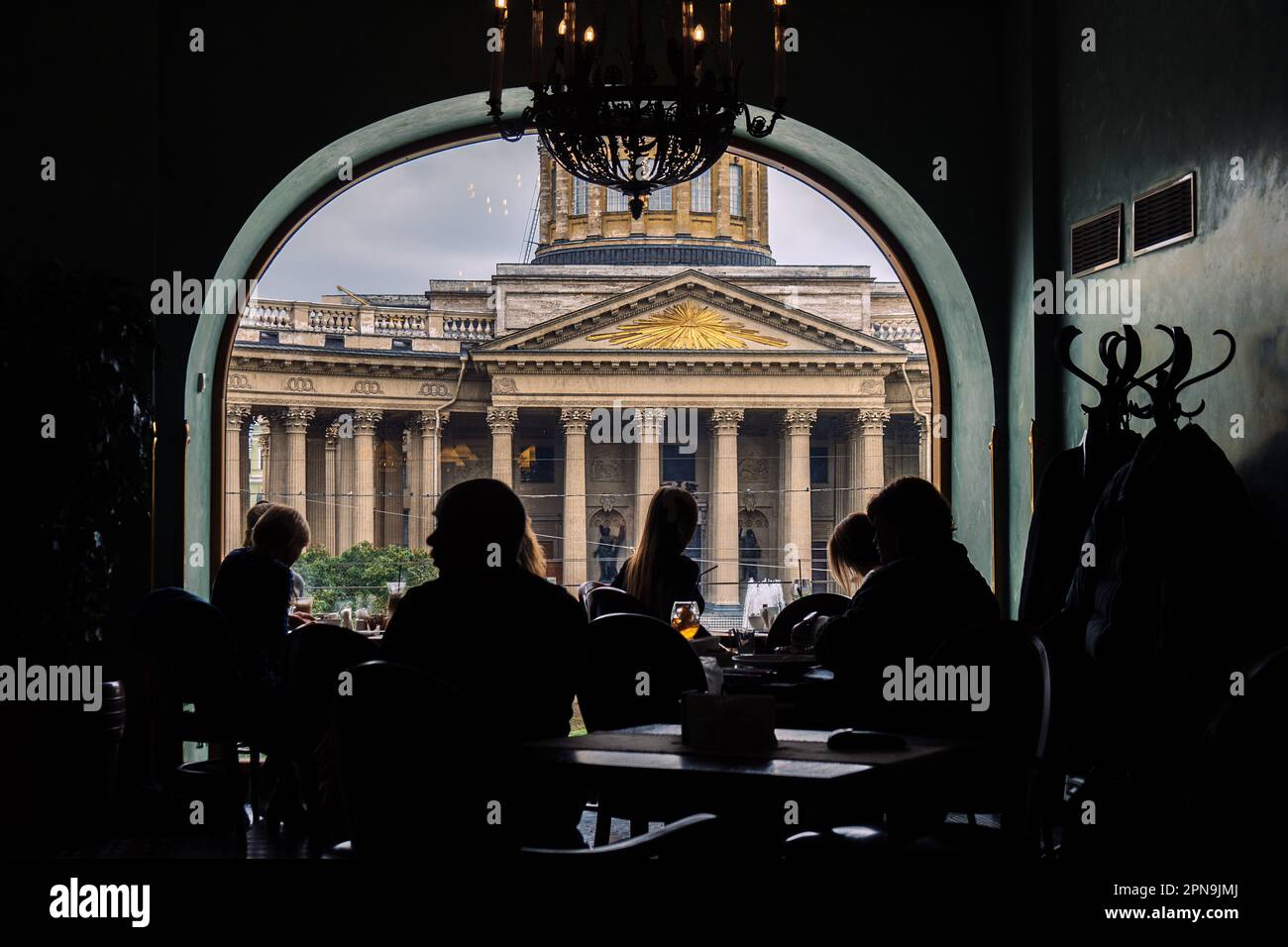 Vista della Cattedrale di Kazan dal Singer Cafe attraverso la finestra. Silhouette di persone sedute ai tavoli nella vecchia Singer House a San Pietroburgo, Russia. Foto di alta qualità Foto Stock