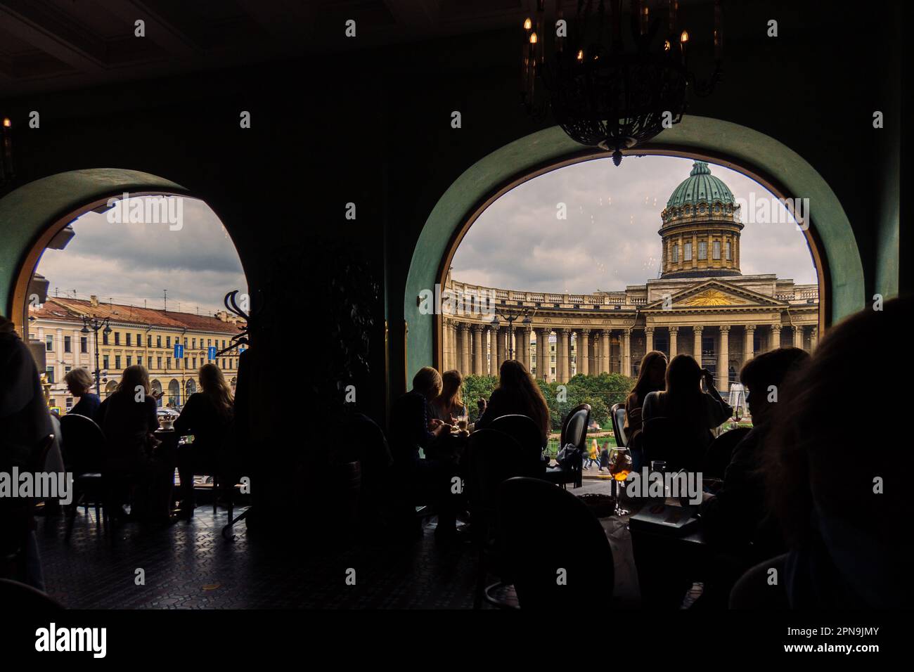 Vista della Cattedrale di Kazan dal Singer Cafe attraverso la finestra. Silhouette di persone sedute ai tavoli nella vecchia Singer House a San Pietroburgo, Russia. Foto di alta qualità Foto Stock