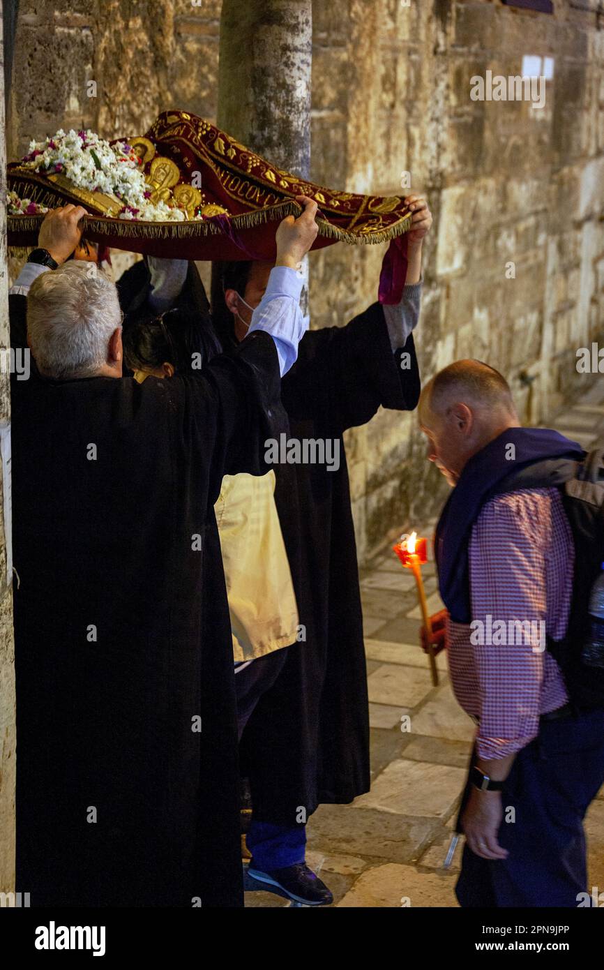 I credenti vengono alla chiesa bizantina di Panagia Kapnikarea durante l'Epitaph (Venerdì Santo), passando sotto un tappeto che rappresenta l'Epitaph. Foto Stock
