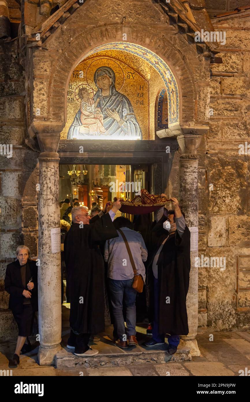 I credenti vengono alla chiesa bizantina di Panagia Kapnikarea durante l'Epitaph (Venerdì Santo), passando sotto un tappeto che rappresenta l'Epitaph. Foto Stock