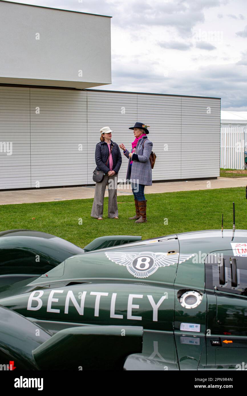 Due donne in piedi accanto alla riunione dei membri delle auto da corsa Bentley al circuito Goodwood Motor di West Sussex, Regno Unito. Foto Stock