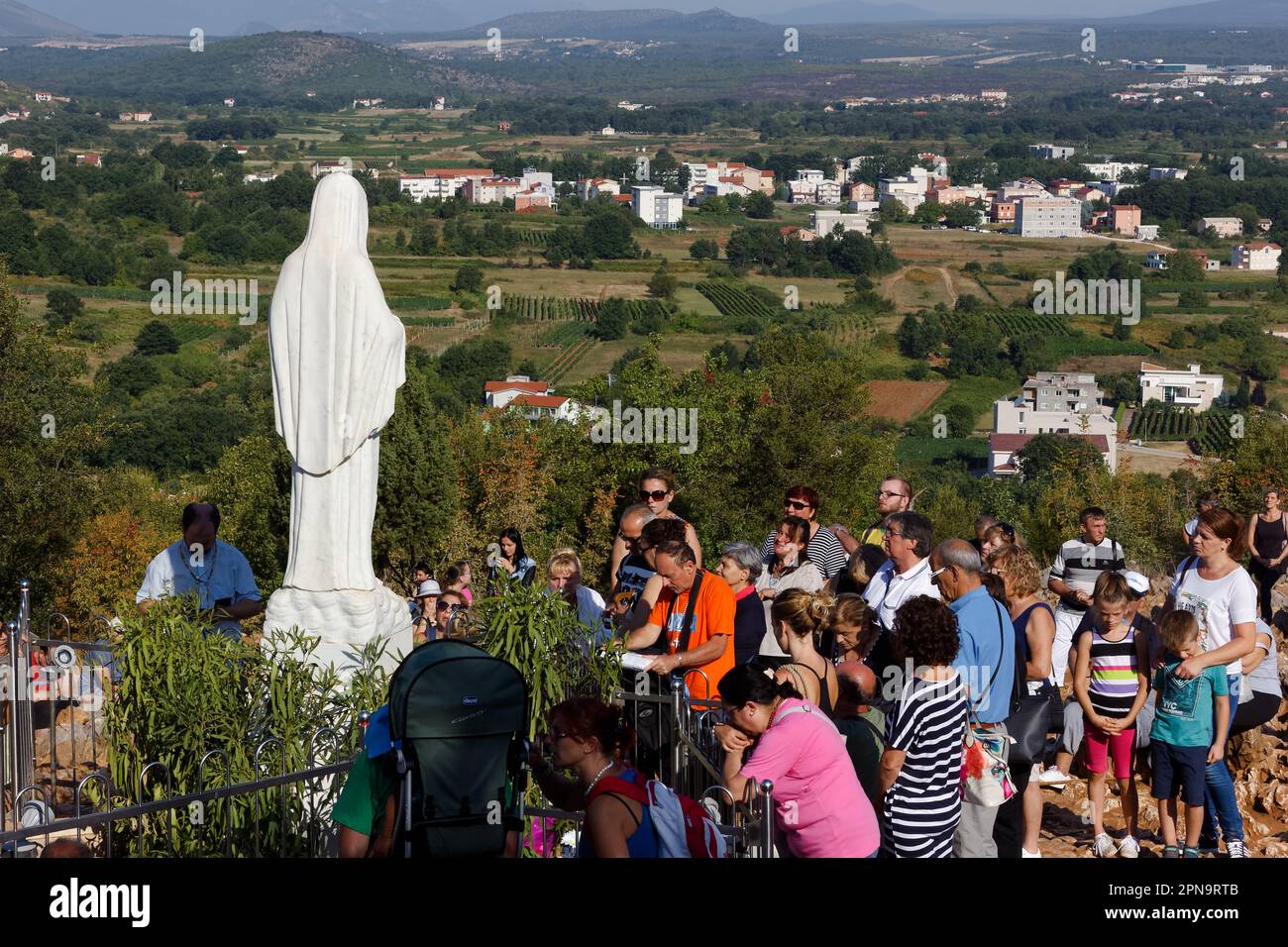 Statua della Vergine Maria, Regina della Pace, sul Monte Podbrdo, circondata da pellegrini in preghiera. Foto Stock