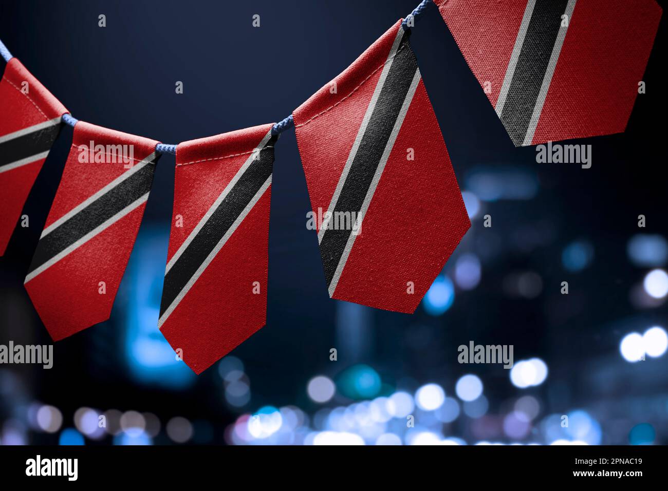 Una ghirlanda di bandiere nazionali di Trinidad e Tobago su un astratto sfondo sfocato. Foto Stock