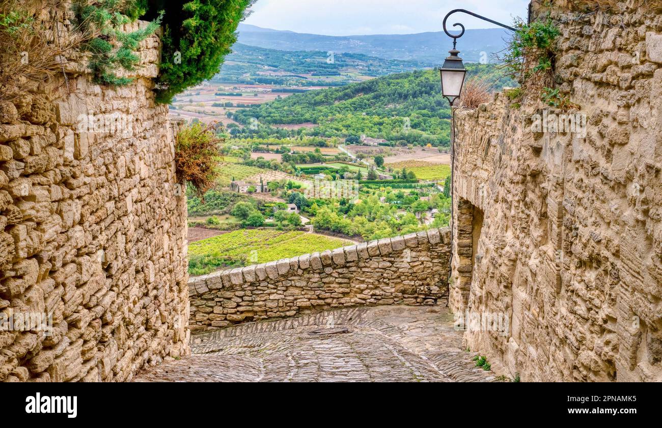 Il borgo medievale di Gordes nella regione del Luberon in Provenza, Francia, si affaccia su un'ampia valle di campi coltivati, frutteti e vigneti sottostanti Foto Stock