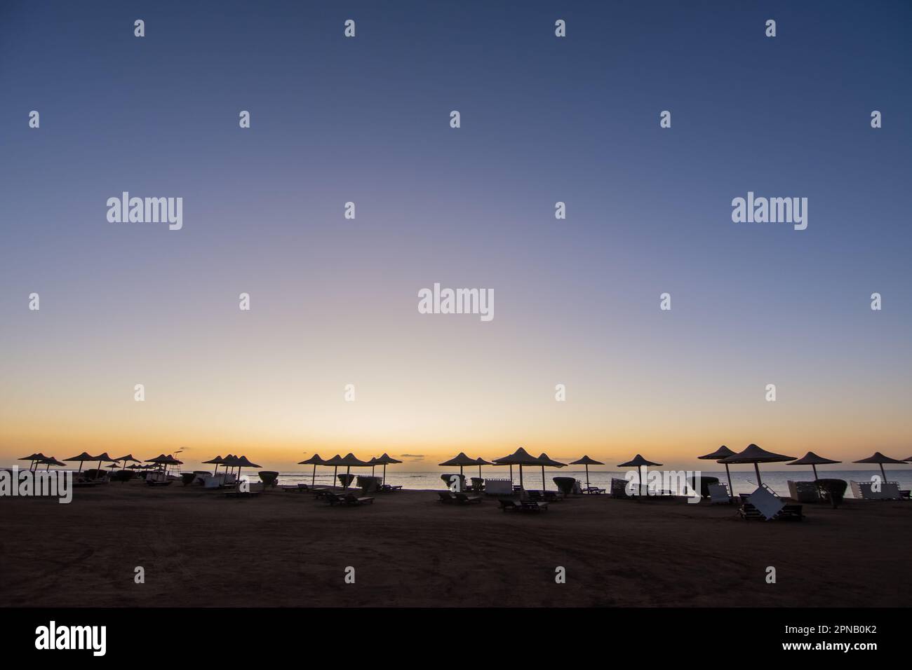 colori incredibili durante l'alba in spiaggia con molti ombrelloni e lettini in egitto Foto Stock