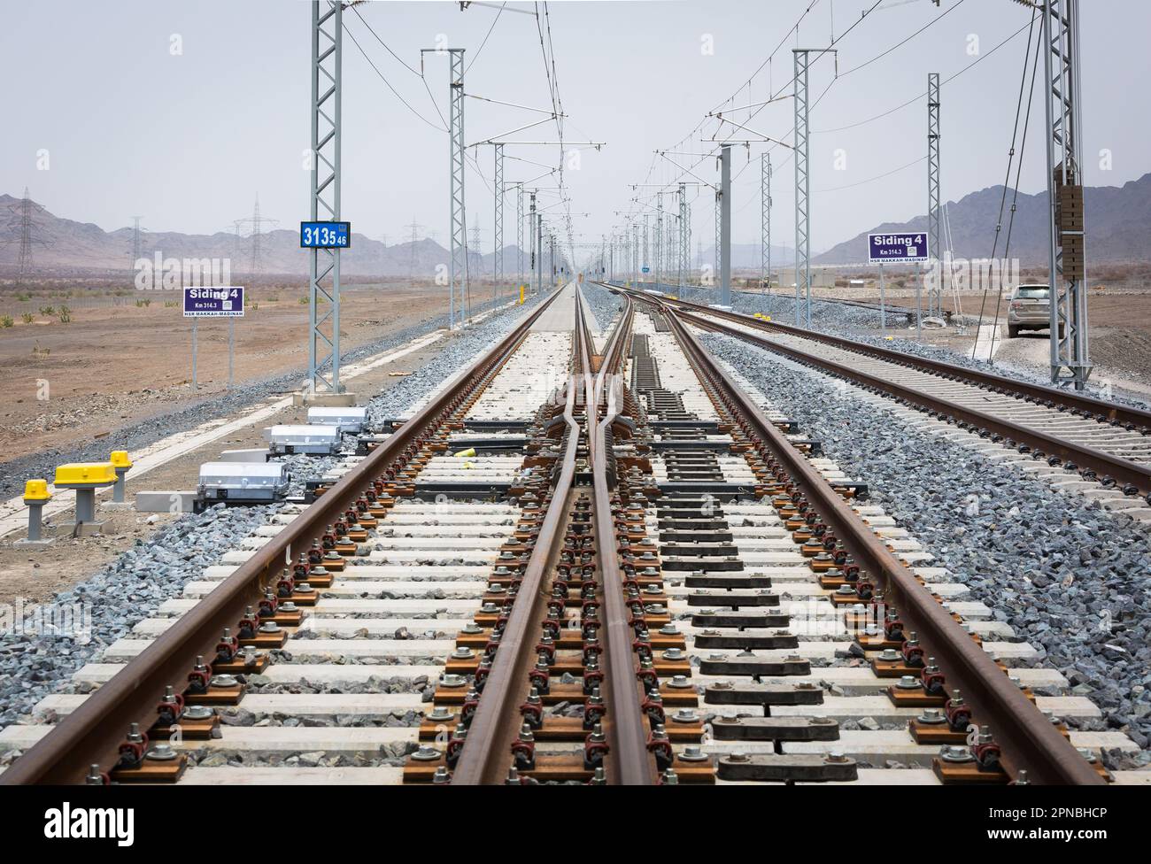 Lunghe rotaie rettilinee per treni che corrono con congiunzione tra rotaie metalliche su terreno roccioso durante il giorno Foto Stock