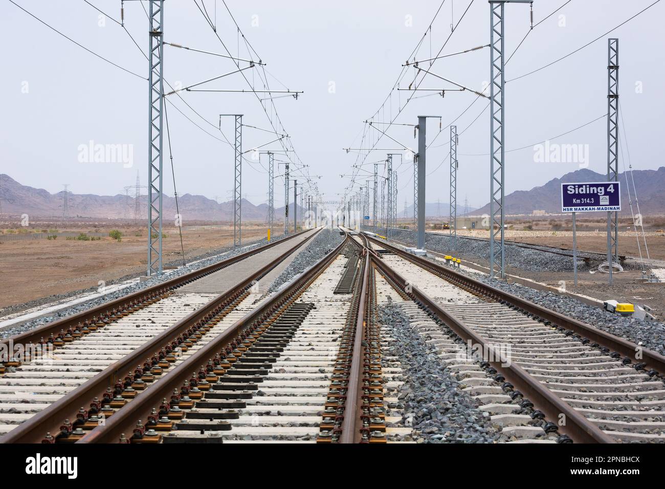 Lunghe rotaie rettilinee per treni che corrono con congiunzione tra rotaie metalliche su terreno roccioso durante il giorno Foto Stock