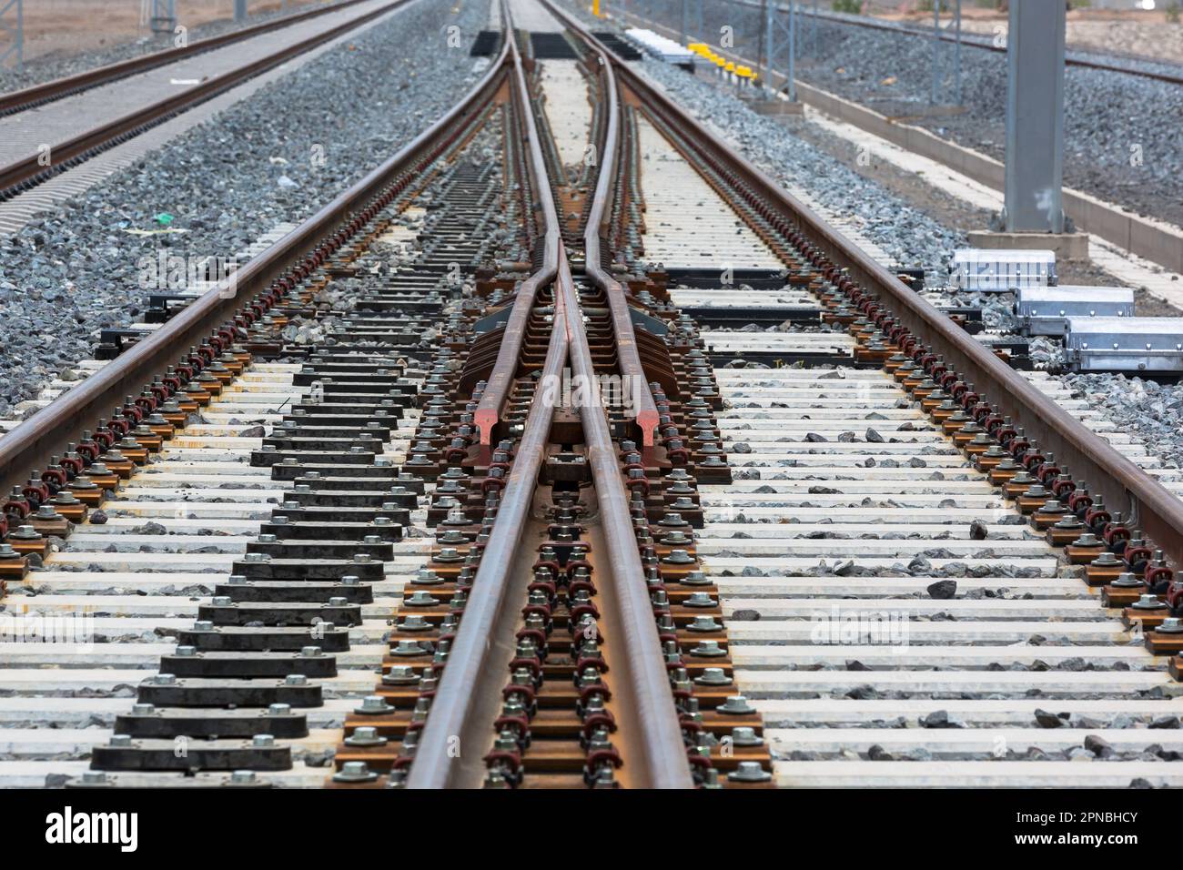 Lunghe rotaie rettilinee per treni che corrono con congiunzione tra rotaie metalliche su terreno roccioso durante il giorno Foto Stock