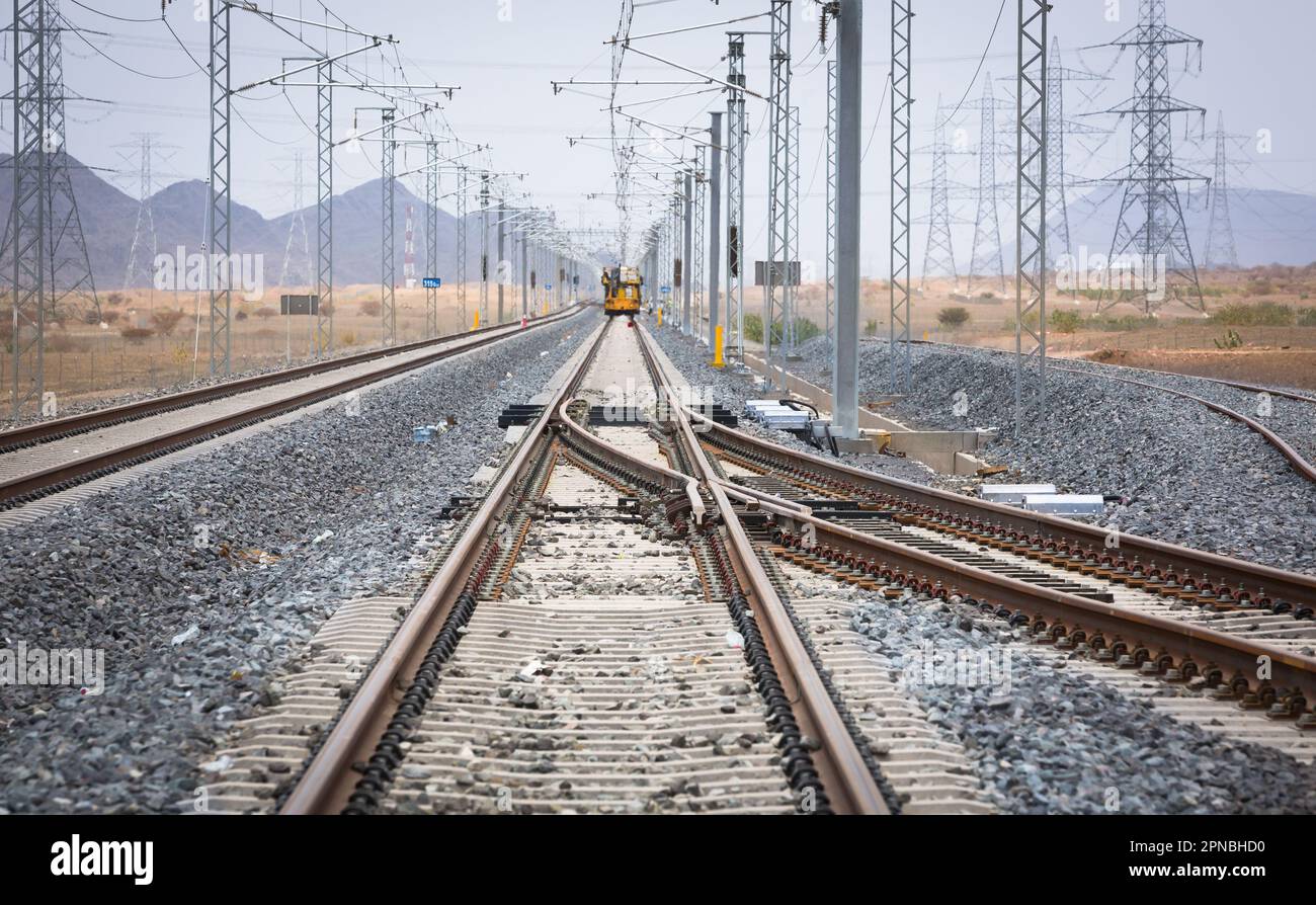 Lunghe rotaie rettilinee per treni che corrono con congiunzione tra rotaie metalliche su terreno roccioso durante il giorno Foto Stock