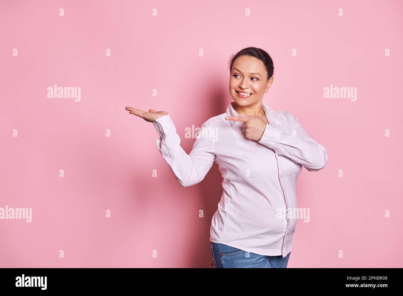 Bella donna buisnesswoman grigio femmina, manager sorride e punta il suo indice dito a copia spazio annuncio sulla sua mano palmo in su Foto Stock