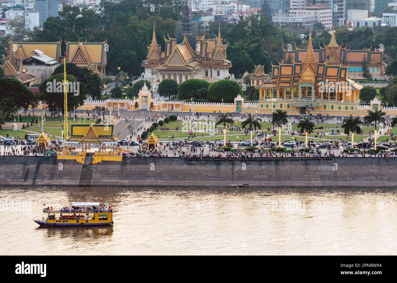 Vista sul tetto, che si affaccia sull'area di Riverside della capitale della Cambogia. Tramonto sul Palazzo reale e gli alti edifici dietro, come una piccola barca Foto Stock