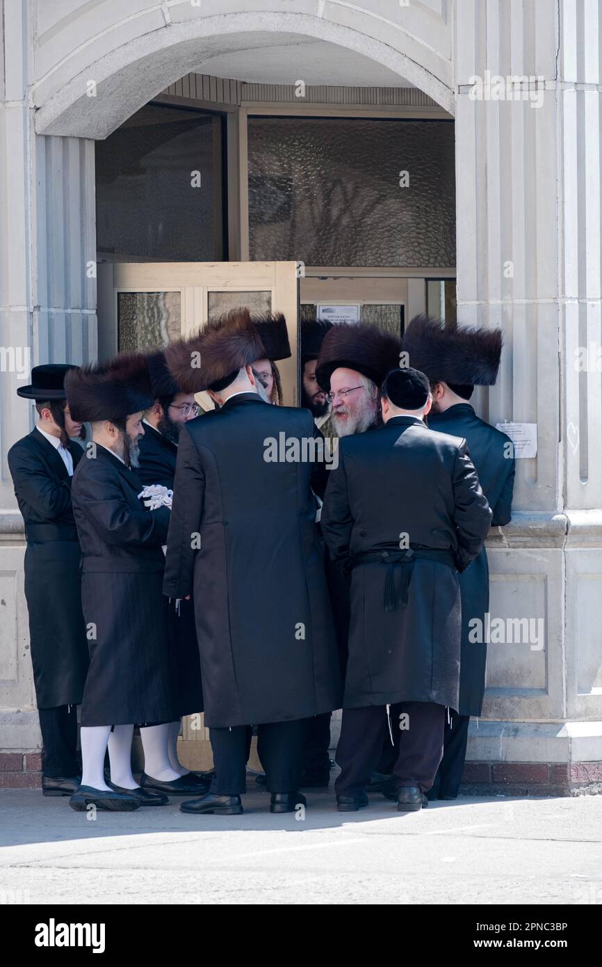Gli ebrei ortodossi del gruppo Satmar si affollano intorno a un oratore. Durante la Pasqua 2023. Molti indossano cappelli di pelliccia di shtreimel. A Brooklyn, New York. Foto Stock