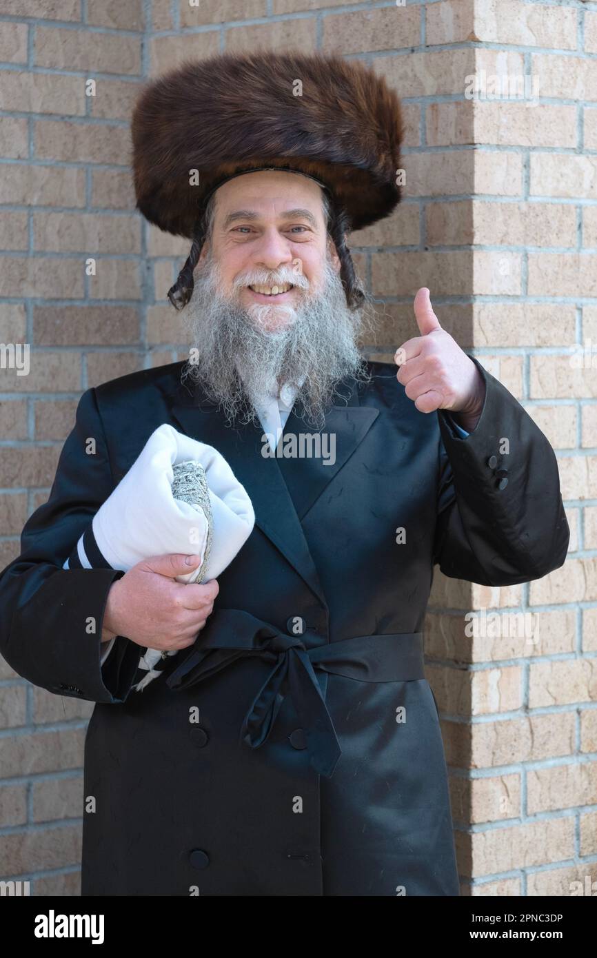 Ritratto pasquale di un felice uomo hassidico che indossa uno shtreimel e tiene un tallis. Passover 2023 a Brooklyn, New York City. Foto Stock
