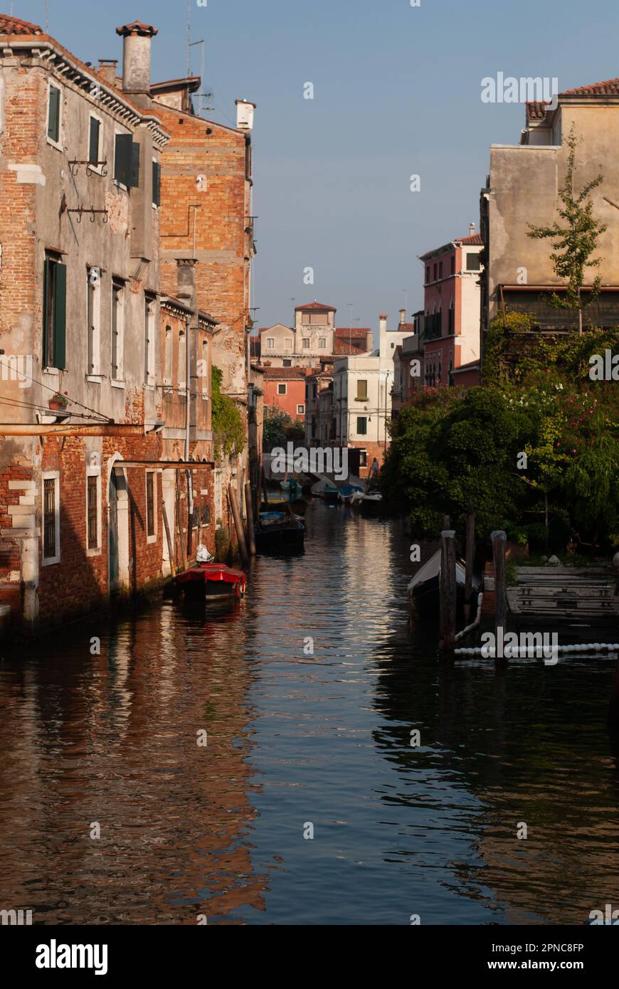 Vista sulle barche sul canale sotto gli edifici alla luce del sole Foto Stock
