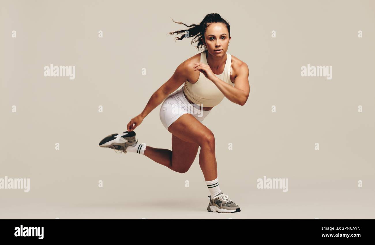 Giovane atleta che esegue esercizi di allenamento di forza in uno studio. Sportswoman mostrando la sua dedizione per migliorare la sua forma fisica e prestazioni Foto Stock