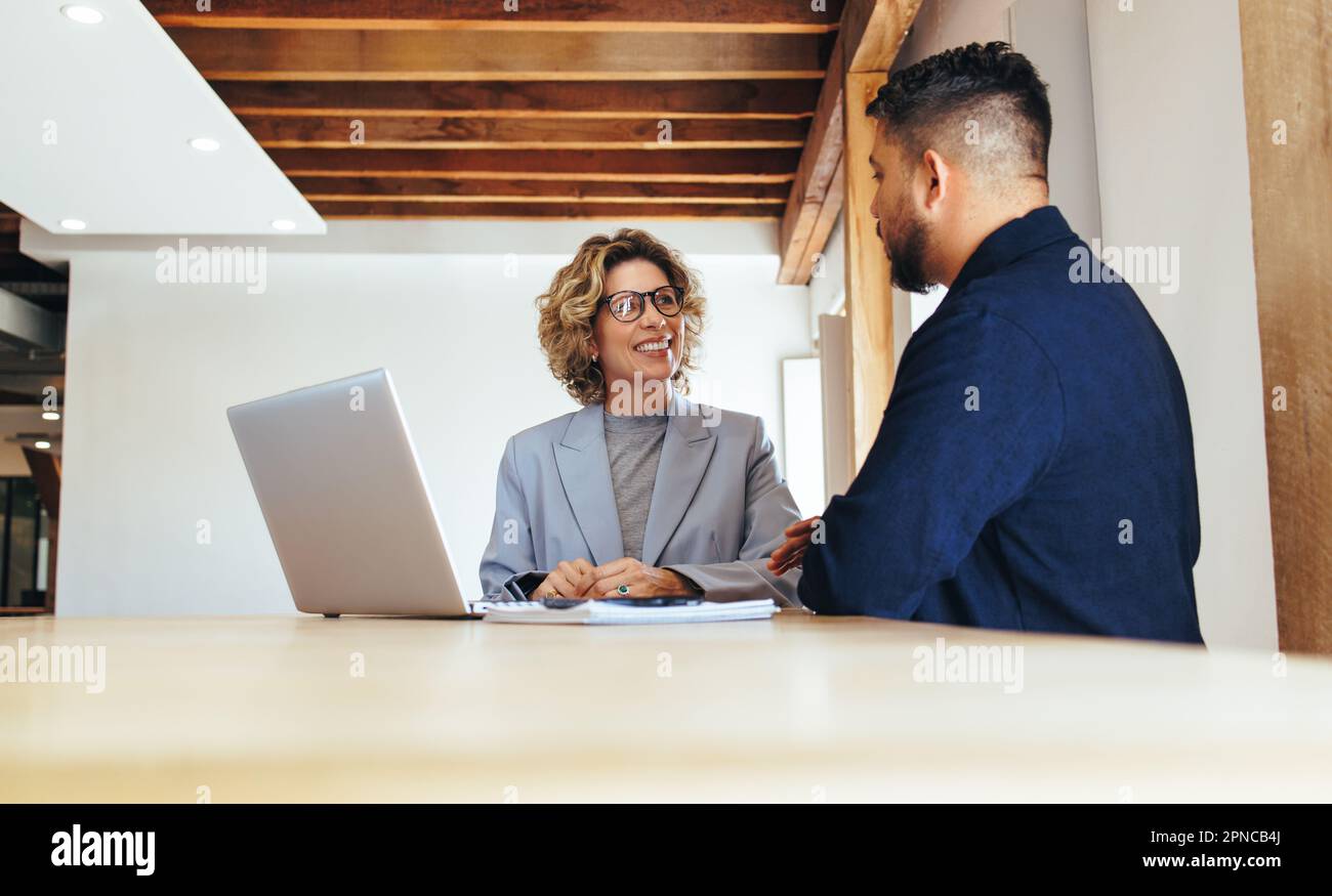 Due uomini d'affari che hanno una riunione. Uomo e donna che parlano in un ufficio. colleghi d'affari che discutono al lavoro. Foto Stock