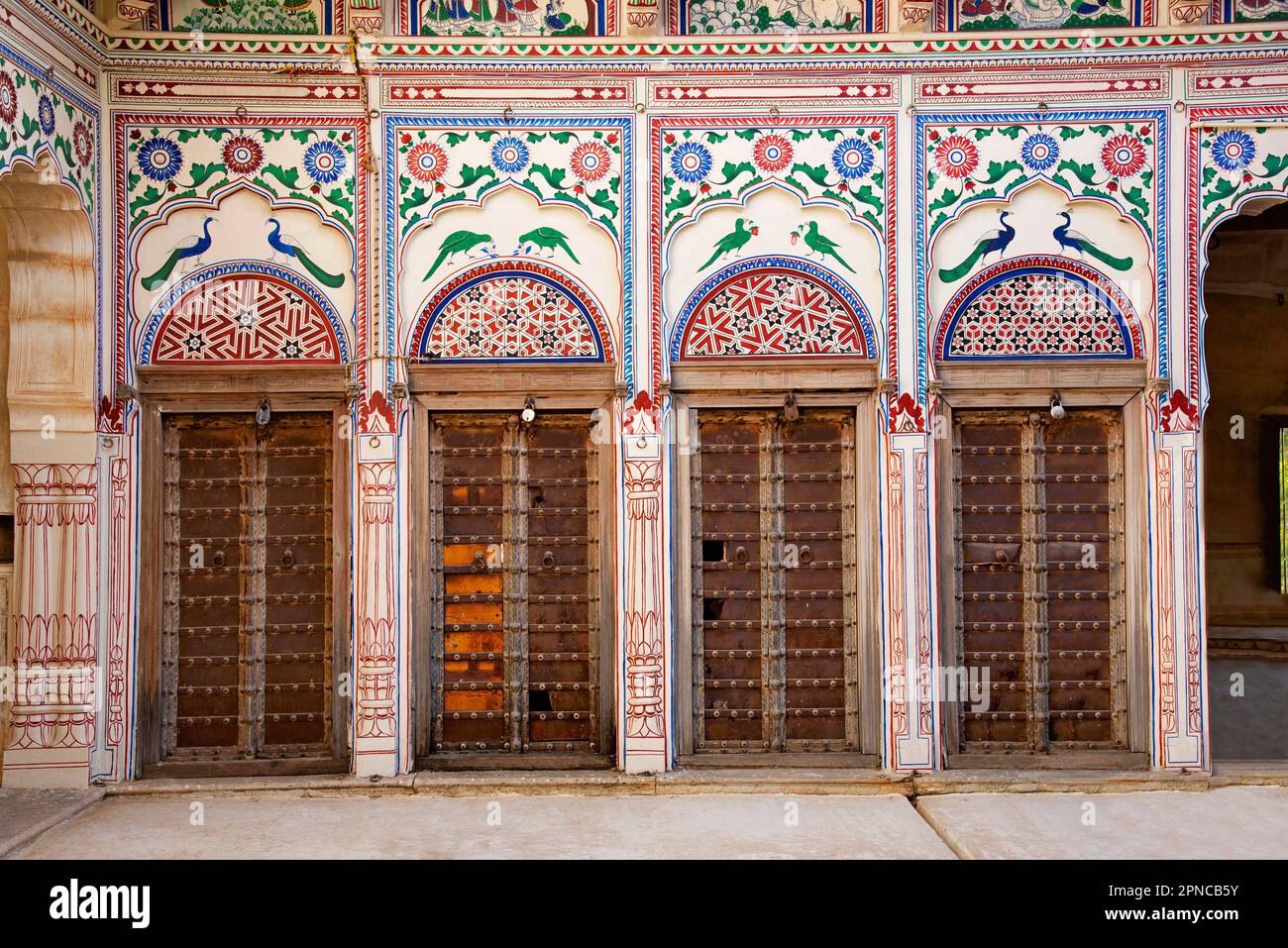 Dipinti colorati e finestre in legno sulla parete esterna di Seth Harmukhrai Sanehiram Chokhani Double Haveli, situato a Mandawa, Shekhawati, Rajastha Foto Stock
