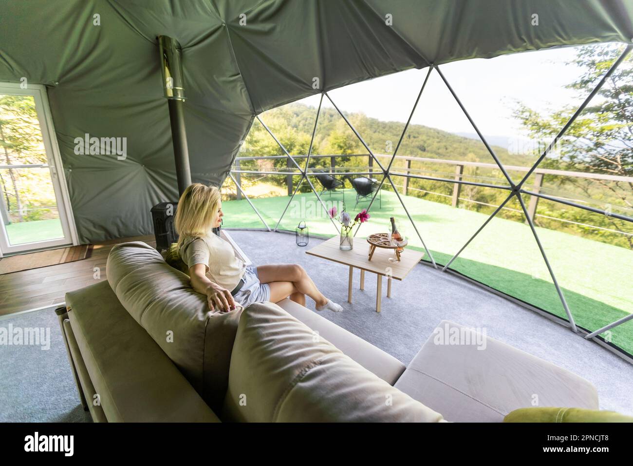 Tenda a bolla trasparente al glamping, lussureggiante foresta intorno e  all'interno. donna che riposa in glamping Foto stock - Alamy