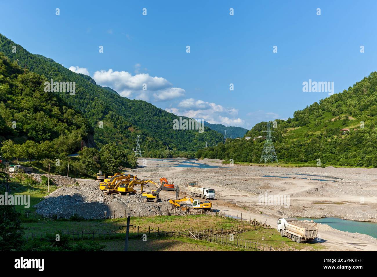 La bonifica del letto del fiume in montagna, le attrezzature da costruzione, gli escavatori e i camion eliminano le conseguenze delle inondazioni primaverili dei fiumi di montagna. Foto Stock