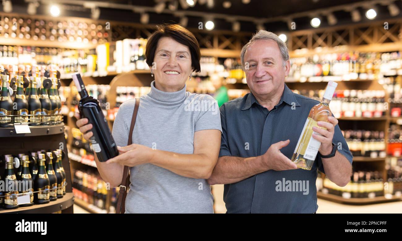 L'uomo anziano e la donna anziana scelgono una bottiglia di alcool Foto Stock