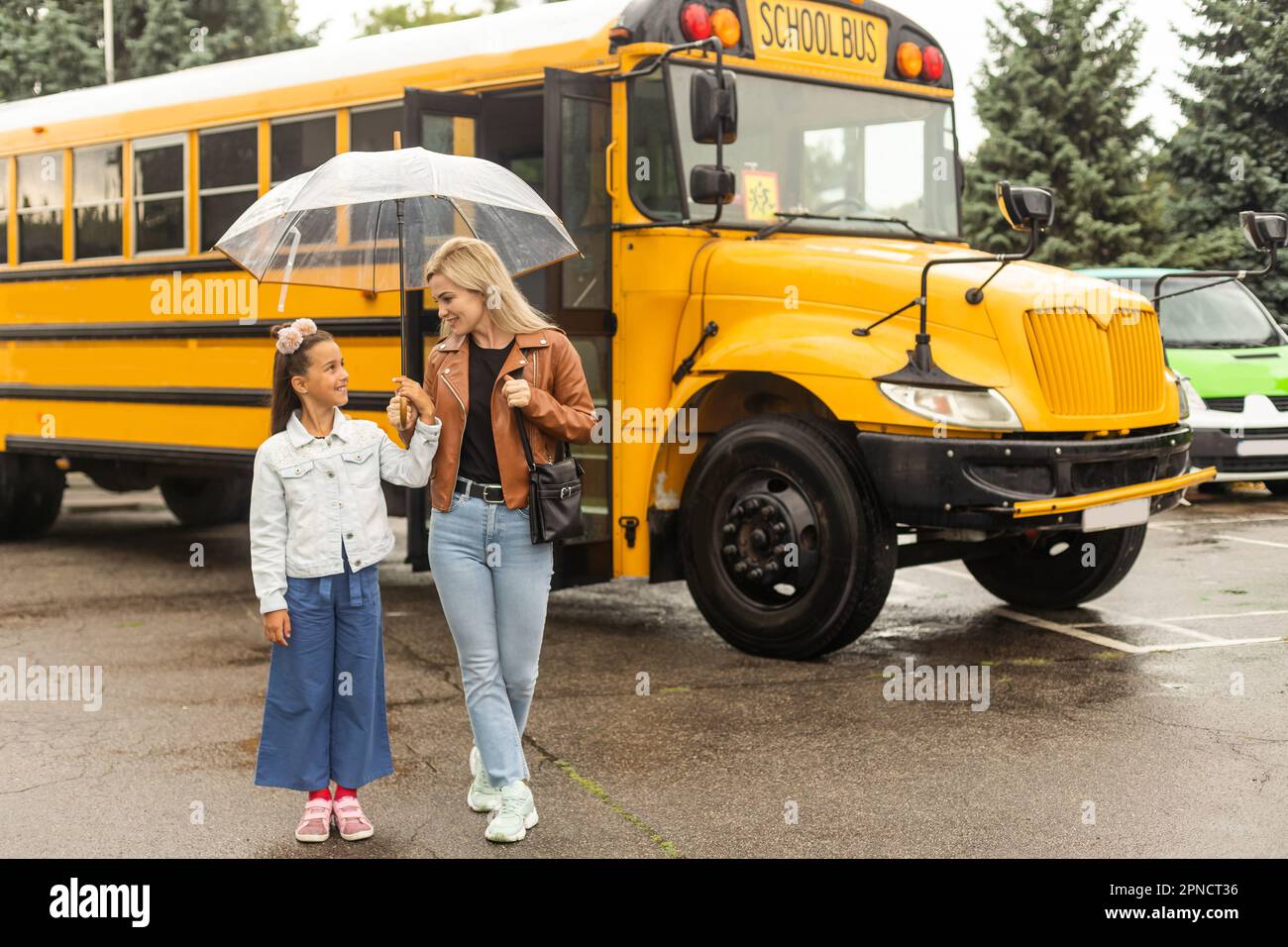 Ritorno a scuola. Alunni della scuola elementare vicino al bus scolastico. Bambini felici pronti a studiare. Bambina con mamma che va in autobus Foto Stock