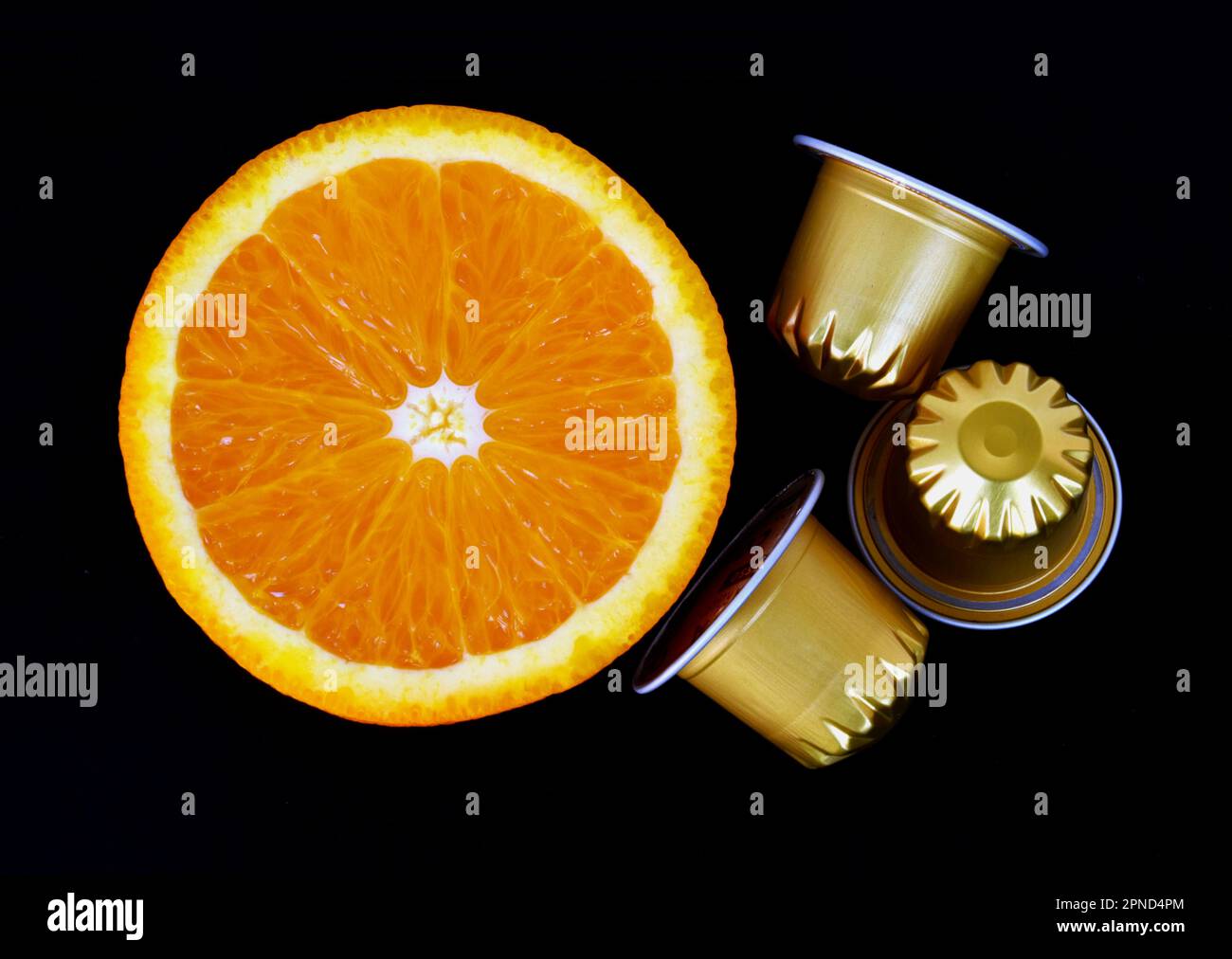 capsule di caffè lucide in alluminio color oro isolato. frutta a fette mezza arancia. concetto di colazione. bevanda calda del mattino e vitamina. composizione astratta Foto Stock