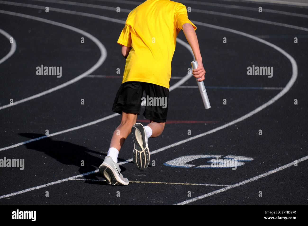 Runner in pista con camicia gialla con batone pronto per una gara Foto Stock