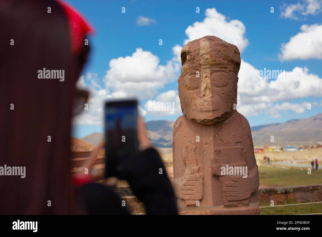 Un turista che scatta una foto con uno smartphone a un monolite a Tiwanaku, un sito archeologico precolombiano nella Bolivia occidentale. Foto Stock