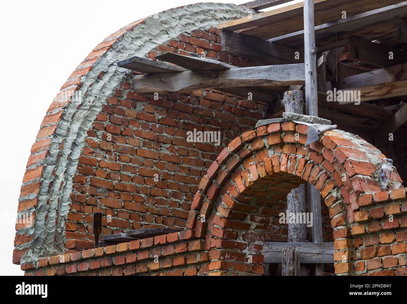 costruzione di un campanile e di una chiesa. Muro di mattoni. Ponteggi in legno Foto Stock
