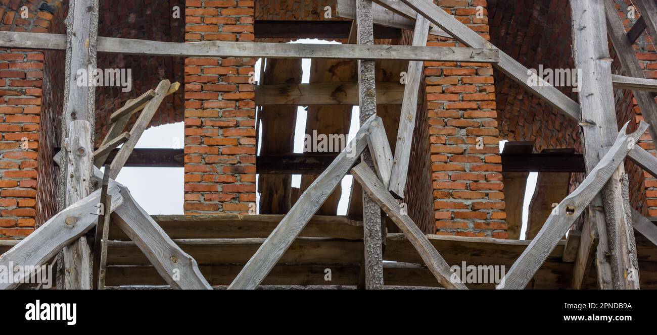 costruzione di un campanile e di una chiesa. Muro di mattoni. Ponteggi in legno Foto Stock