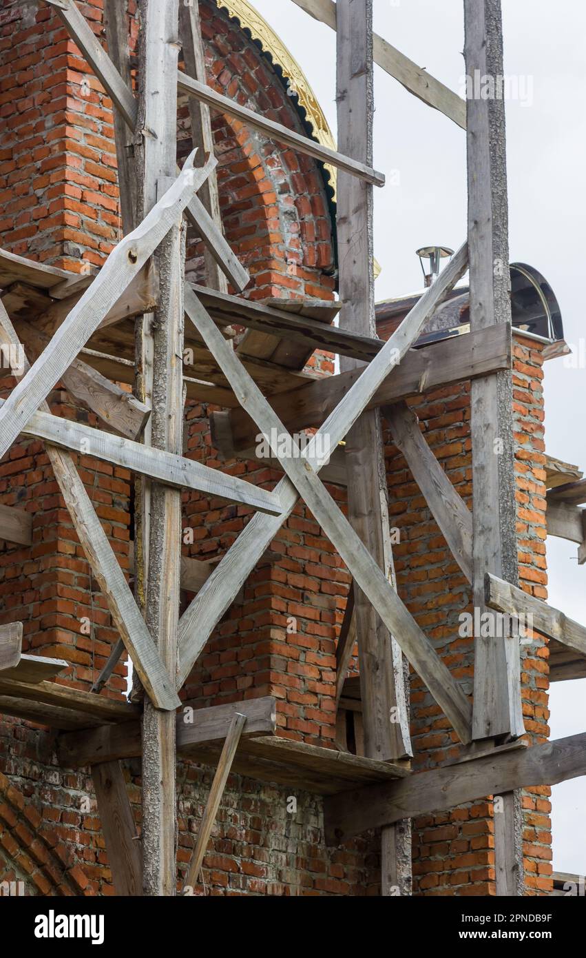 costruzione di un campanile e di una chiesa. Muro di mattoni. Ponteggi in legno Foto Stock