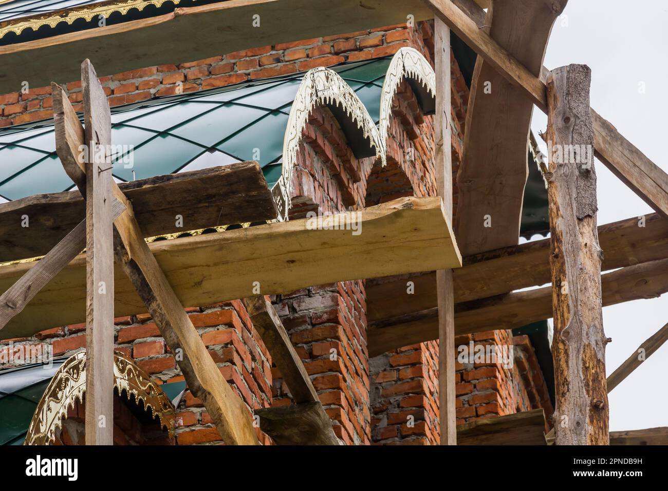 costruzione di un campanile e di una chiesa. Muro di mattoni. Ponteggi in legno Foto Stock