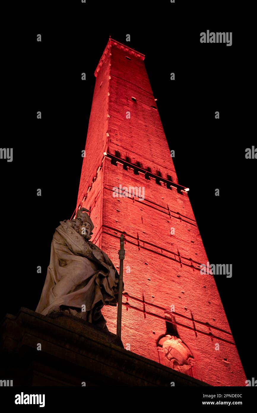 La torre medievale Garisenda e la statua di San Petronio illuminato di notte nella botte storica di Bologna, Emilia Romagna, Italia. Foto Stock