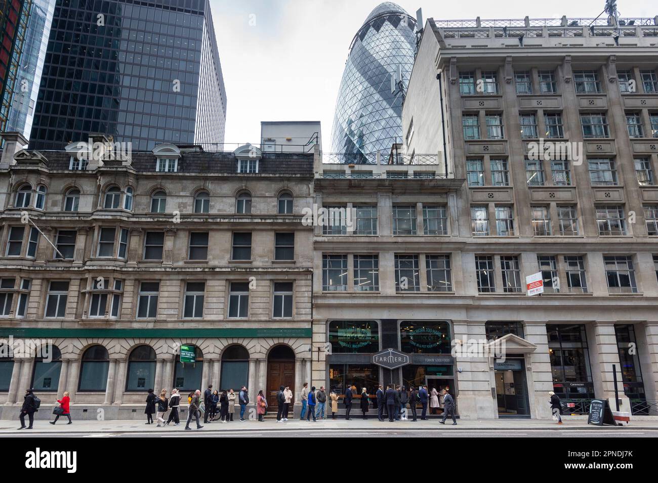 Londra, Regno Unito. 18 aprile 2023. L'edificio Gherkin, visto dietro i lavoratori della città in coda per il pranzo in un ristorante nella città di Londra. L'Ufficio per le statistiche nazionali (ONS) ha riferito che i guadagni medi, esclusi i bonus, sono aumentati del 6,6% nei tre mesi fino a febbraio rispetto a un anno fa. Gli economisti hanno commentato che la Banca d’Inghilterra potrebbe alzare i tassi di interesse dall’attuale livello del 4,25% quando la sua commissione per la politica monetaria si riunirà il prossimo 11 maggio per combattere l’inflazione. Credit: Stephen Chung / Alamy Live News Foto Stock