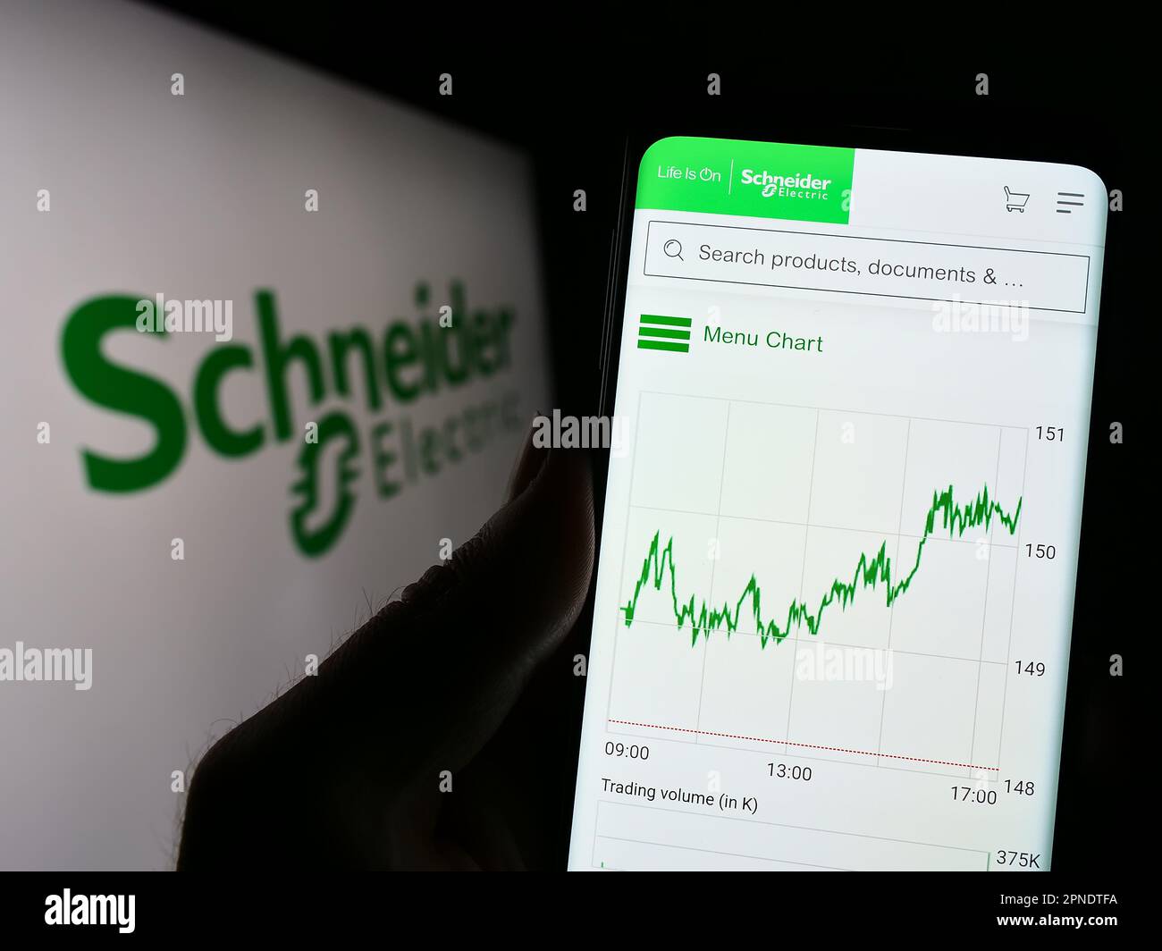 Persona che tiene il cellulare con il sito web della società francese Schneider Electric se sullo schermo di fronte al logo. Messa a fuoco al centro del display del telefono. Foto Stock