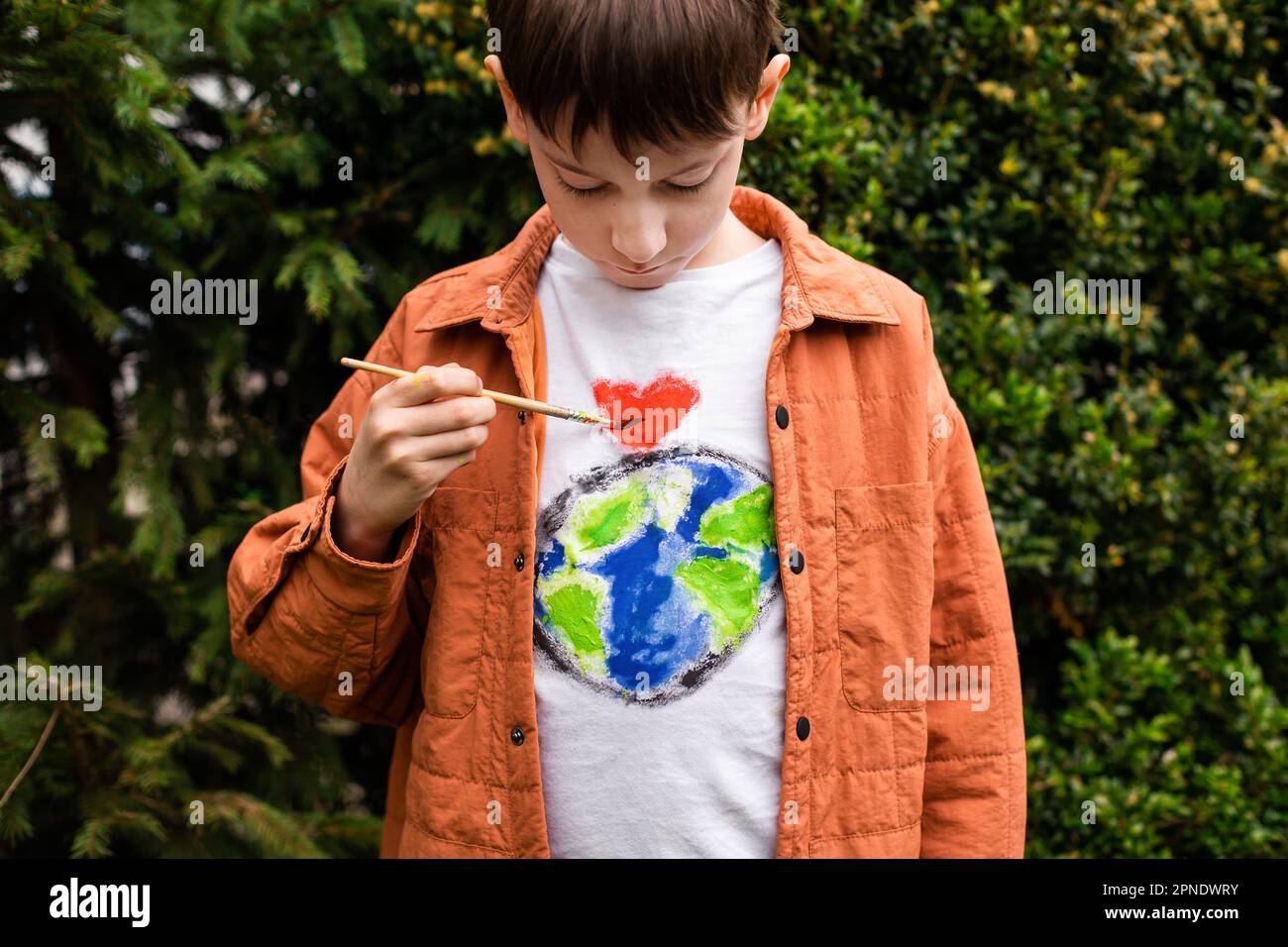 Concetto di stile di vita sostenibile. Scolaro che disegna il globo della terra sulla t-shirt. Energia verde, ESG, risorse rinnovabili, tutela dell'ambiente, protezione del pianeta Foto Stock