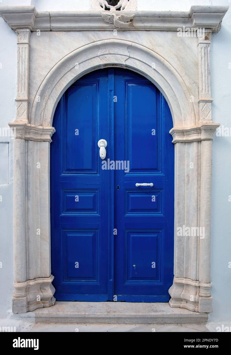 Grecia. Isola d'arte di Tinos, porta d'ingresso casa blu con arco in marmo su pareti bianche, architettura cicladica al villaggio di Pyrgos Foto Stock