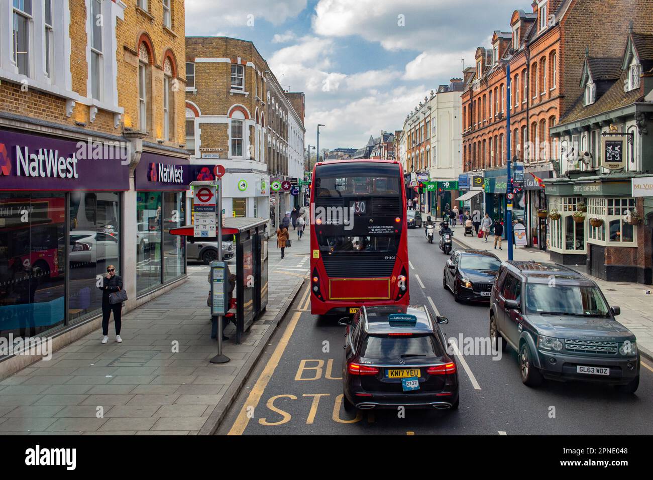 Putney High St, Putney, Londra; tipica strada dello shopping britannica, affollata di traffico e autobus rossi Foto Stock