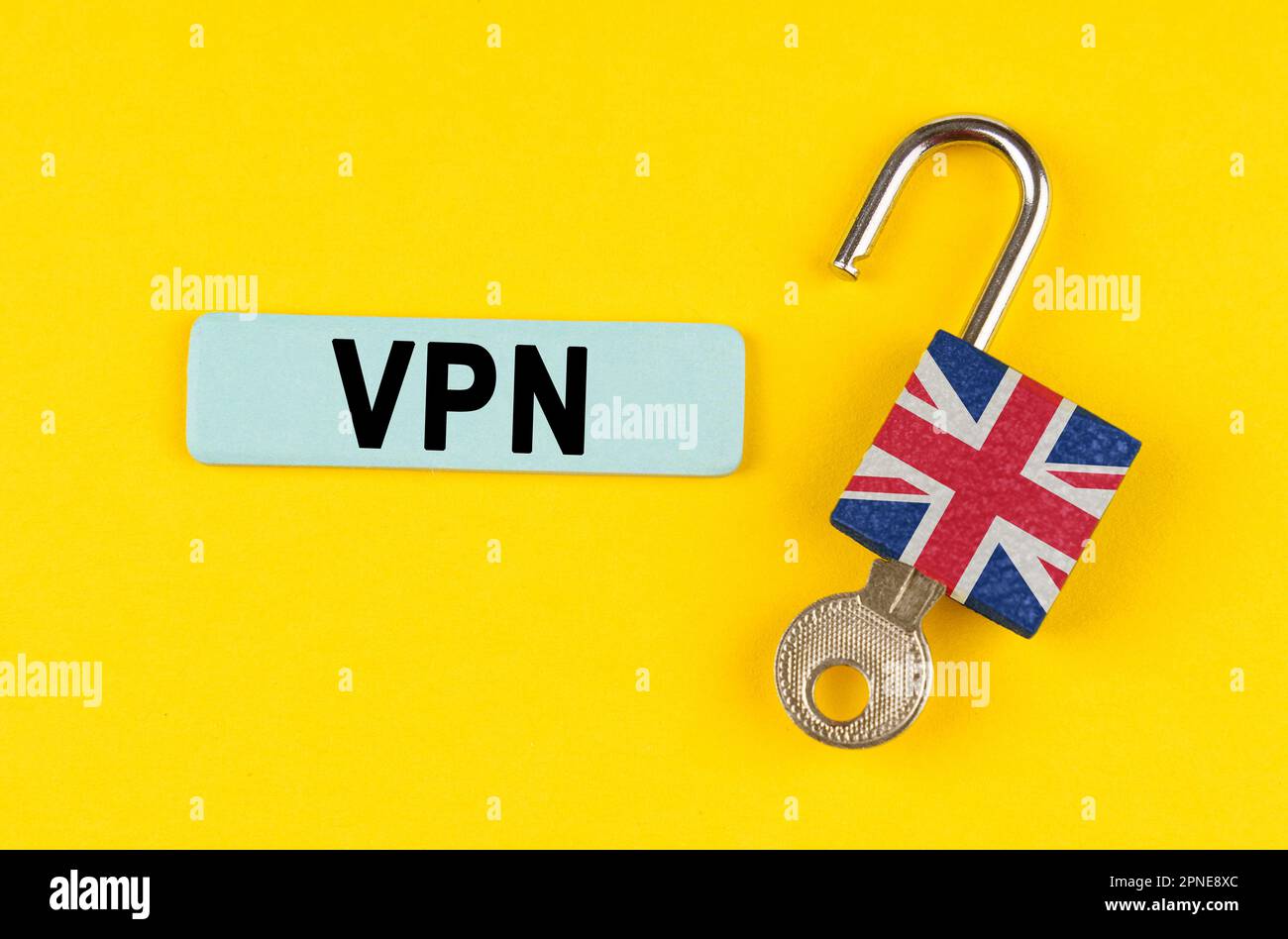 Su una superficie gialla, un lucchetto aperto con l'immagine della bandiera della Gran Bretagna con una chiave e un adesivo con l'iscrizione - VPN Foto Stock