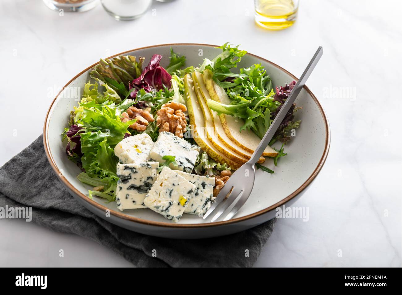 Insalata sana a base di foglie di insalata verde, insalata di rucola, fette di pere fresche, pezzi di formaggio blu, noci e semi di sesamo. Foto Stock
