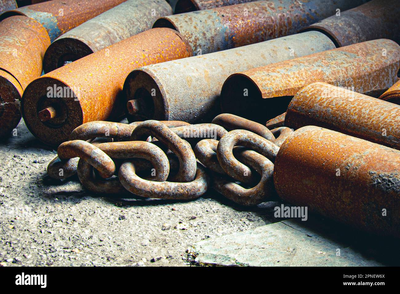 Catena arrugginita e cilindri metallici in una vecchia fabbrica Foto Stock