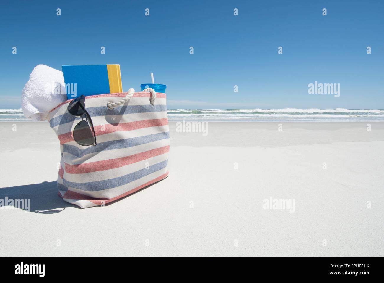Borsa da spiaggia con asciugamano, libro e occhiali da sole sulla spiaggia, Topsail Island Foto Stock